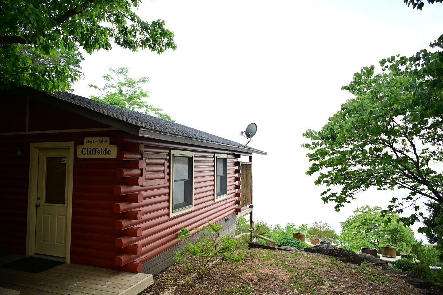 Red log cabin with a private deck perched on the limestone bluff above the White River