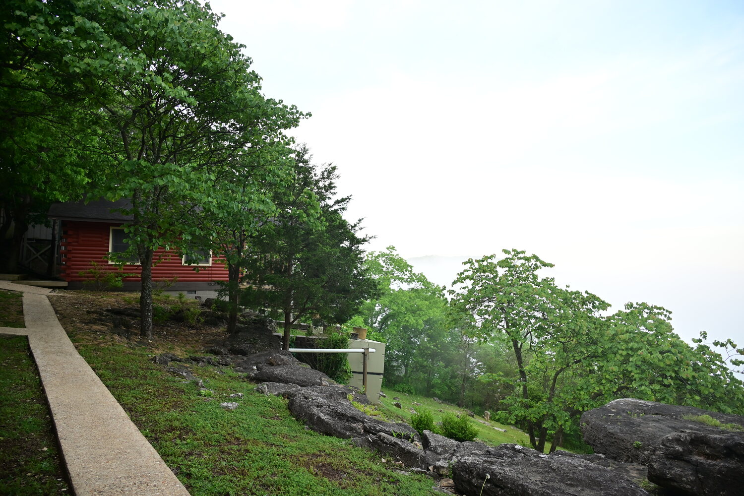 Red log cabin with a walkway and valley view in soft morning light