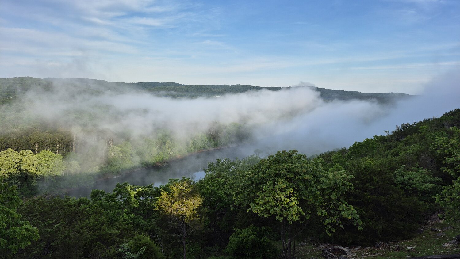 Morning fog rolling over the green forested hills below the cabins