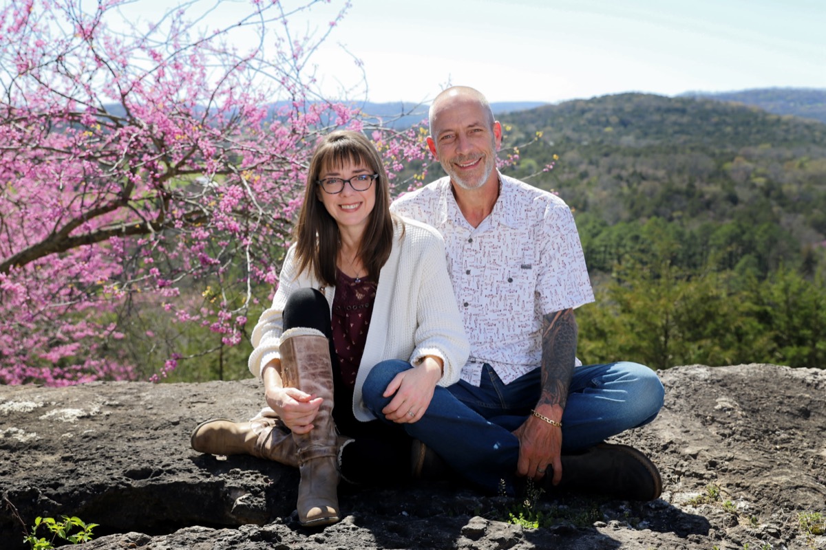Art and Amy sitting on the cliff at White River Cabins with spring blossoms